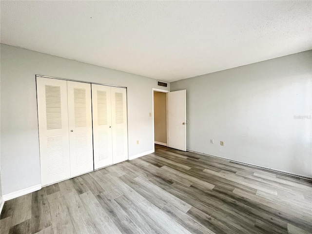 unfurnished bedroom with light hardwood / wood-style floors, a closet, and a textured ceiling