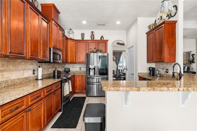 kitchen featuring a kitchen breakfast bar, kitchen peninsula, light tile patterned flooring, appliances with stainless steel finishes, and tasteful backsplash