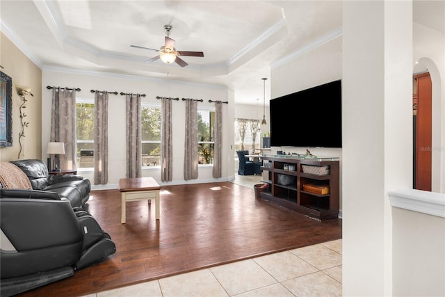 living room featuring crown molding, ceiling fan with notable chandelier, a tray ceiling, and light hardwood / wood-style floors