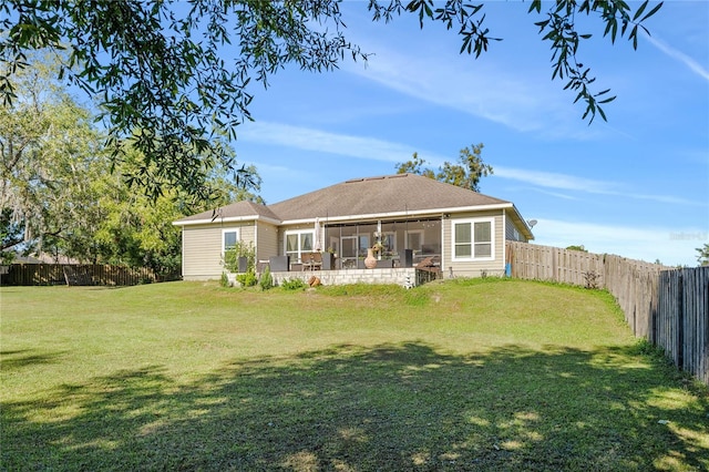 back of property with a sunroom and a lawn