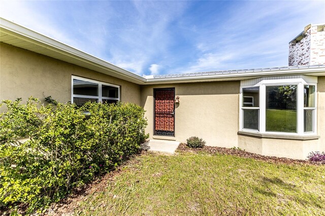 doorway to property featuring a lawn