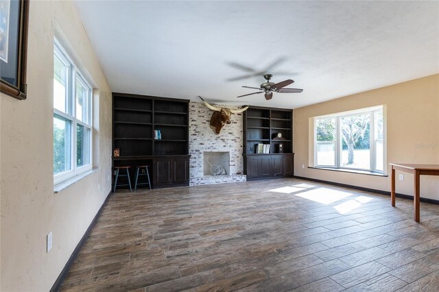 unfurnished living room featuring built in shelves, dark hardwood / wood-style floors, and plenty of natural light