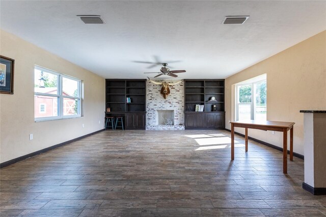 unfurnished living room with dark hardwood / wood-style flooring, a wealth of natural light, and built in shelves