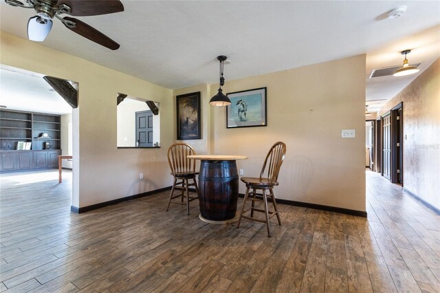 dining area featuring ceiling fan, dark hardwood / wood-style flooring, and built in shelves