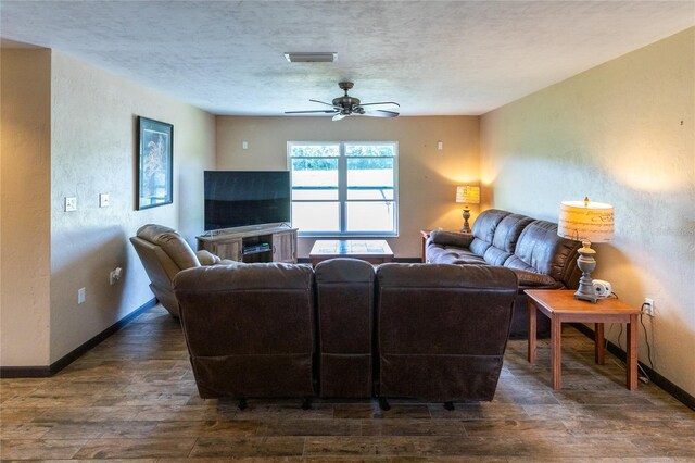 living room featuring dark hardwood / wood-style floors, a textured ceiling, a fireplace, and ceiling fan