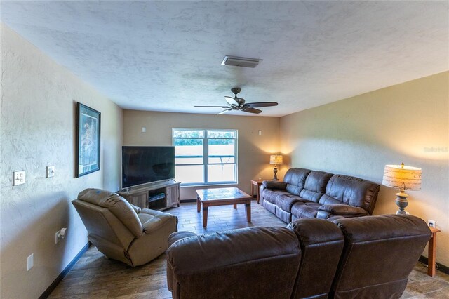 living room featuring ceiling fan, a textured ceiling, and hardwood / wood-style floors