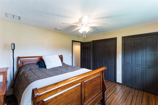 bedroom featuring multiple closets, dark wood-type flooring, and ceiling fan