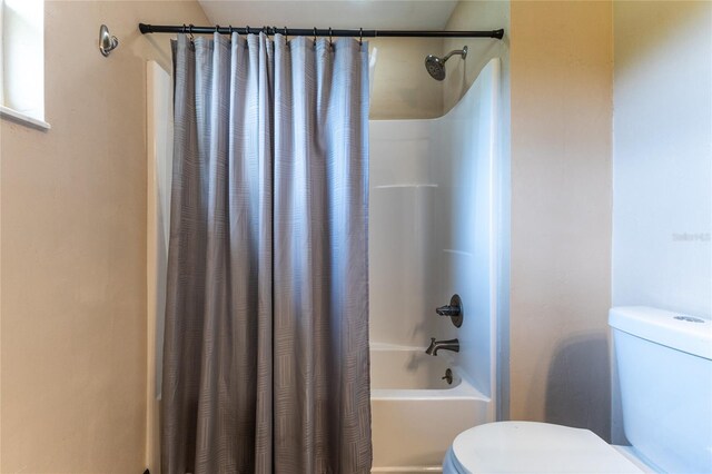 bathroom featuring toilet and shower / bathtub combination with curtain