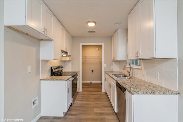 kitchen featuring light stone counters, white cabinetry, light hardwood / wood-style flooring, sink, and stainless steel appliances