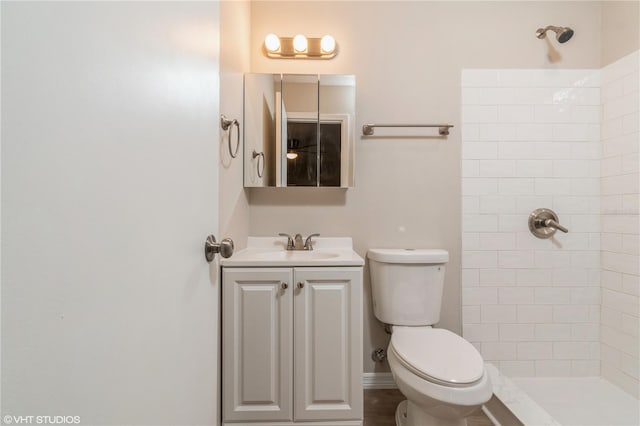 bathroom featuring vanity, toilet, and tiled shower