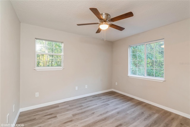 empty room featuring ceiling fan, light hardwood / wood-style flooring, and a wealth of natural light