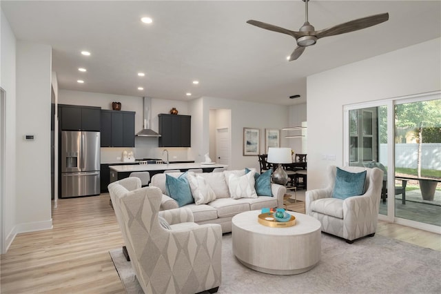 living room with ceiling fan, sink, and light wood-type flooring