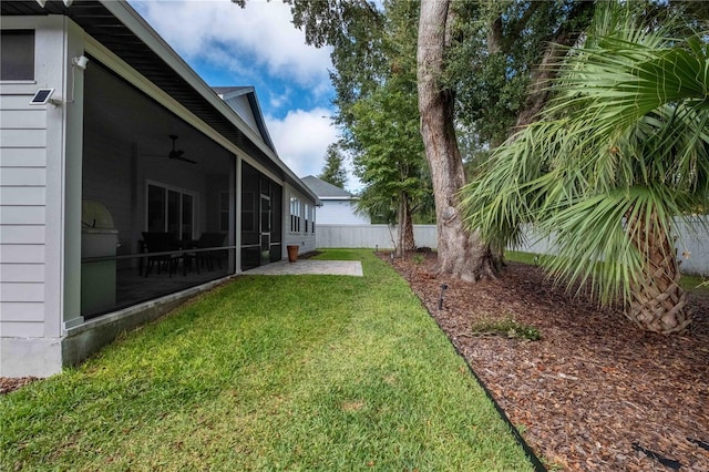 view of yard with a sunroom, ceiling fan, and a patio area