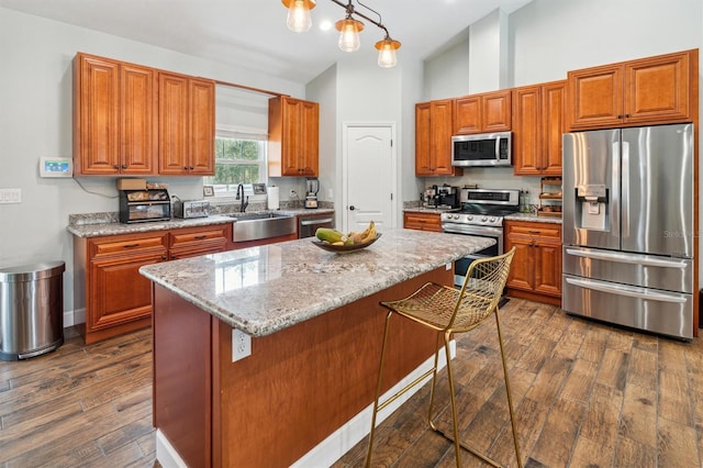 kitchen with a center island, appliances with stainless steel finishes, pendant lighting, and dark hardwood / wood-style flooring