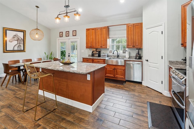 kitchen with sink, a kitchen island, stainless steel appliances, decorative light fixtures, and dark hardwood / wood-style floors