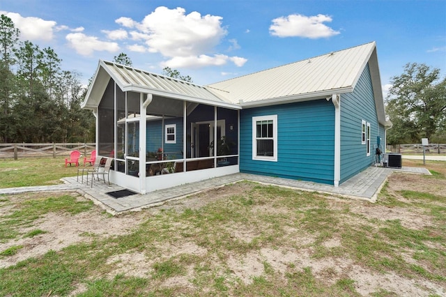 back of property with central air condition unit, a lawn, and a sunroom