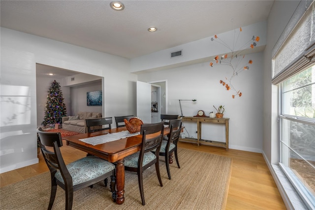 dining area with light hardwood / wood-style floors and a textured ceiling