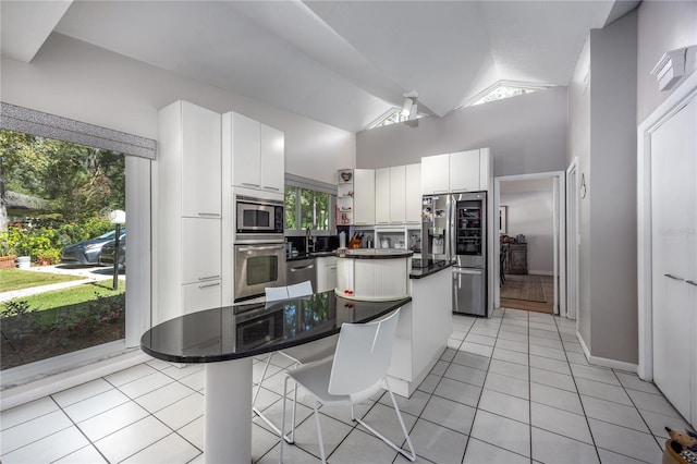 kitchen featuring a kitchen bar, white cabinetry, light tile patterned floors, and appliances with stainless steel finishes