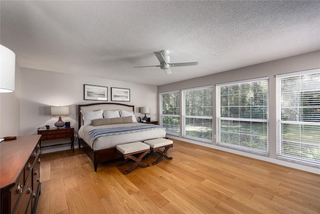 bedroom featuring light wood-type flooring, a textured ceiling, and ceiling fan