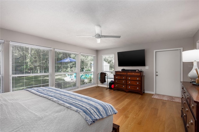 bedroom with ceiling fan, a textured ceiling, and light hardwood / wood-style flooring