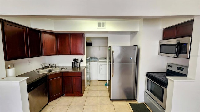 kitchen featuring sink, light tile patterned flooring, washing machine and clothes dryer, and appliances with stainless steel finishes