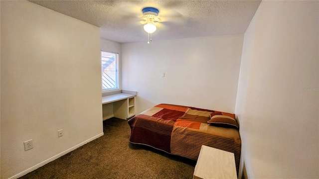 bedroom featuring ceiling fan, dark carpet, and a textured ceiling