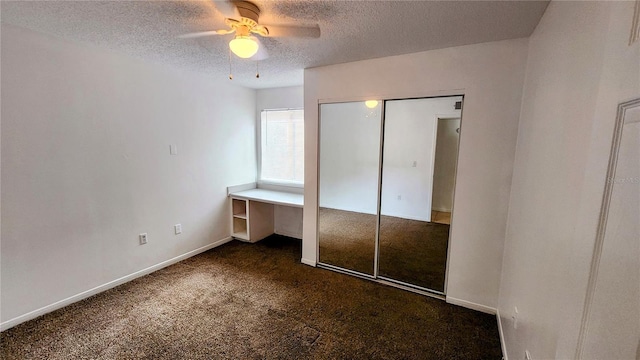 unfurnished bedroom with ceiling fan, dark carpet, a closet, and a textured ceiling