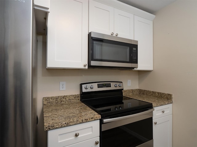 kitchen with appliances with stainless steel finishes, dark stone counters, and white cabinets