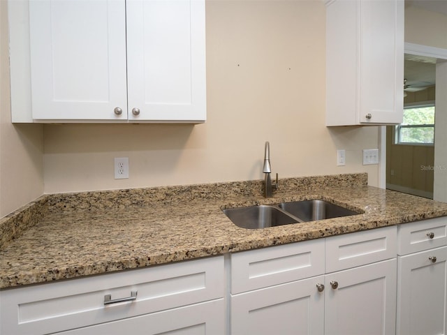 kitchen with sink, white cabinets, and light stone counters