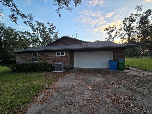 property exterior at dusk featuring a garage, a yard, and central air condition unit