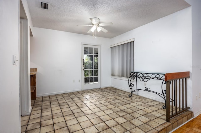 unfurnished room featuring baseboards, visible vents, a textured ceiling, and ceiling fan