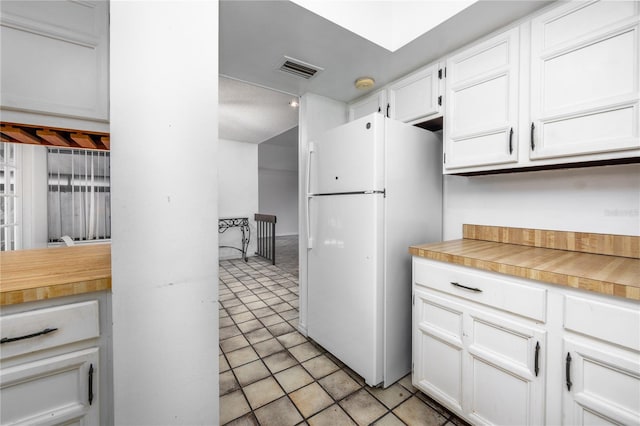 kitchen with visible vents, light tile patterned flooring, freestanding refrigerator, light countertops, and white cabinets