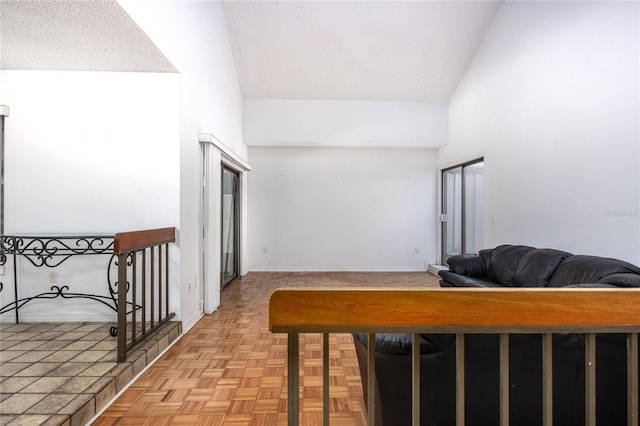 corridor with baseboards, a high ceiling, and a textured ceiling