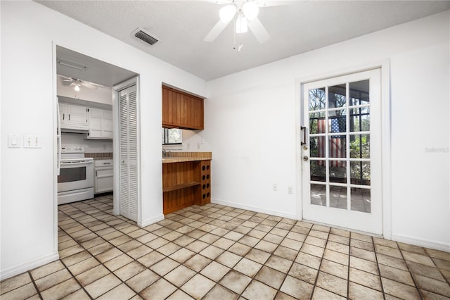 kitchen with electric range, visible vents, under cabinet range hood, a textured ceiling, and ceiling fan