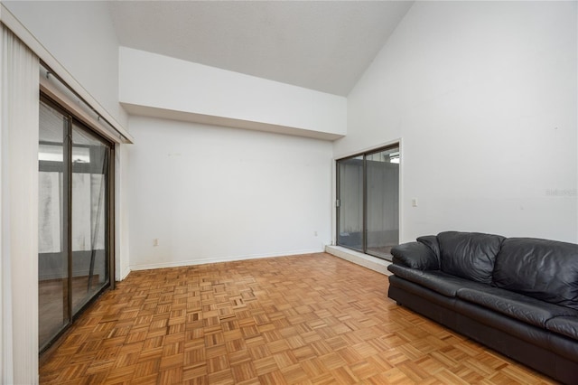 living area with a textured ceiling, high vaulted ceiling, and baseboards