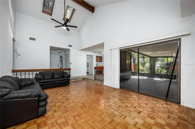 living area featuring beamed ceiling, visible vents, high vaulted ceiling, a skylight, and ceiling fan