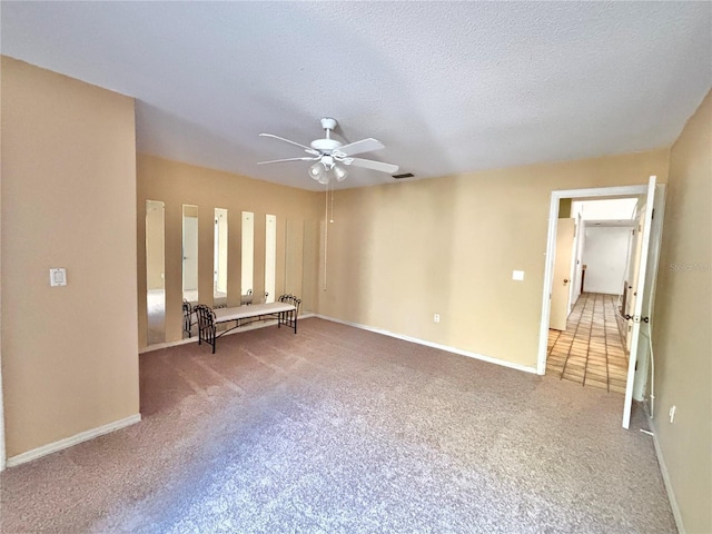 interior space featuring visible vents, baseboards, carpet floors, a textured ceiling, and a ceiling fan