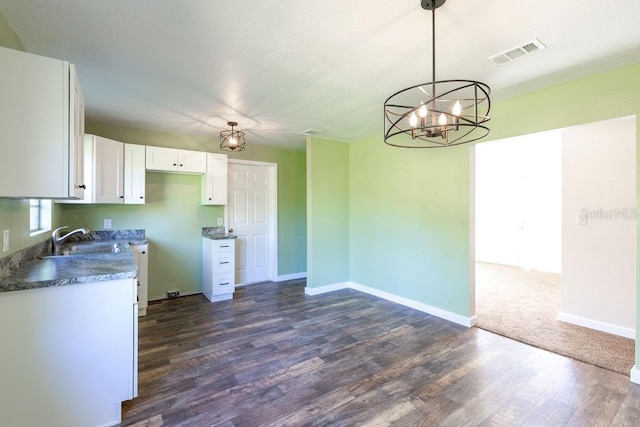 kitchen with white cabinets, a chandelier, dark wood-type flooring, pendant lighting, and sink