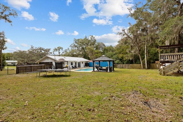 view of yard featuring a gazebo, a fenced in pool, and a trampoline