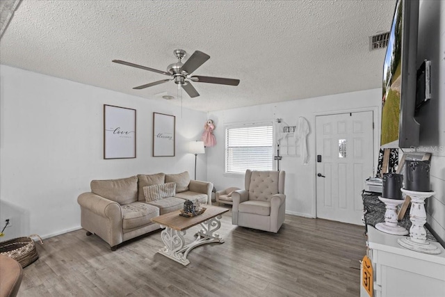 living room with ceiling fan, a textured ceiling, and hardwood / wood-style floors