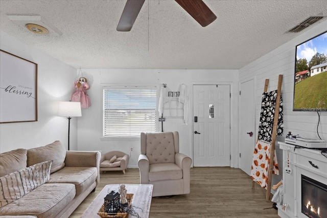 living room featuring ceiling fan, a textured ceiling, and hardwood / wood-style flooring