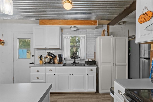 kitchen featuring decorative backsplash, sink, white cabinets, and a healthy amount of sunlight