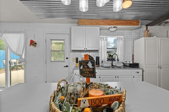 kitchen with a wealth of natural light, white cabinetry, decorative backsplash, and sink