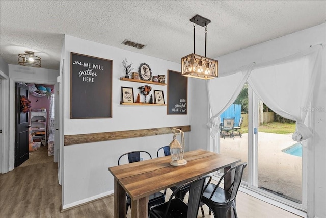 dining space featuring a textured ceiling and hardwood / wood-style floors