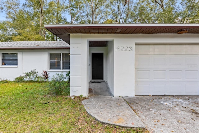 view of exterior entry featuring a lawn and a garage