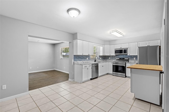 kitchen featuring white cabinets, light wood-type flooring, appliances with stainless steel finishes, and tasteful backsplash