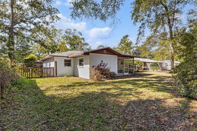 rear view of property featuring a sunroom and a yard