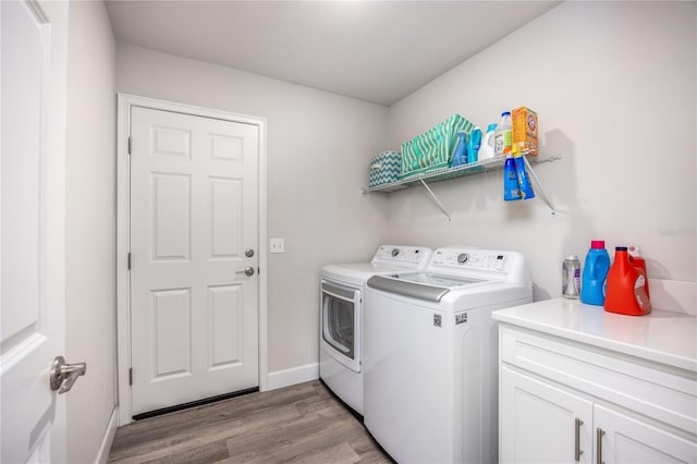 clothes washing area featuring washing machine and dryer, light hardwood / wood-style flooring, and cabinets