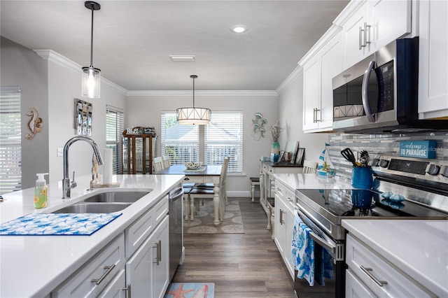 kitchen featuring white cabinets, dark hardwood / wood-style flooring, appliances with stainless steel finishes, decorative light fixtures, and sink