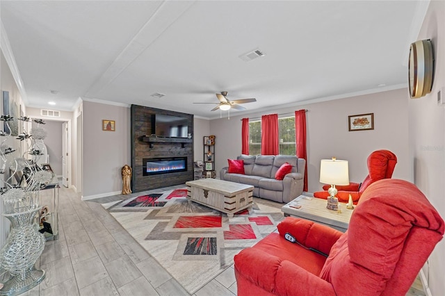 living room with light hardwood / wood-style flooring, ornamental molding, ceiling fan, and a stone fireplace